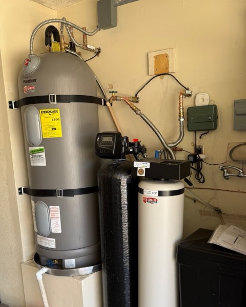 Electric tank water heater in a Las Vegas garage, held by two seismic straps and set in a metal drain pan with a drain line