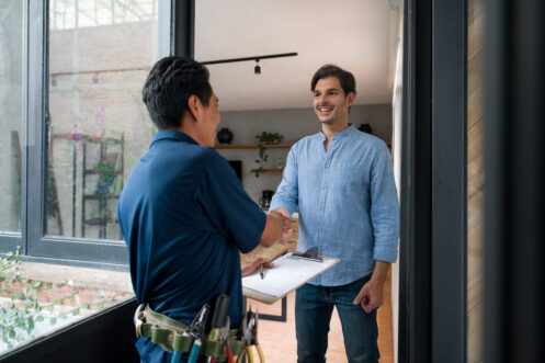 Service technician shaking hands with a homeowner at the front door, emphasizing trust and reliability in plumbing services.